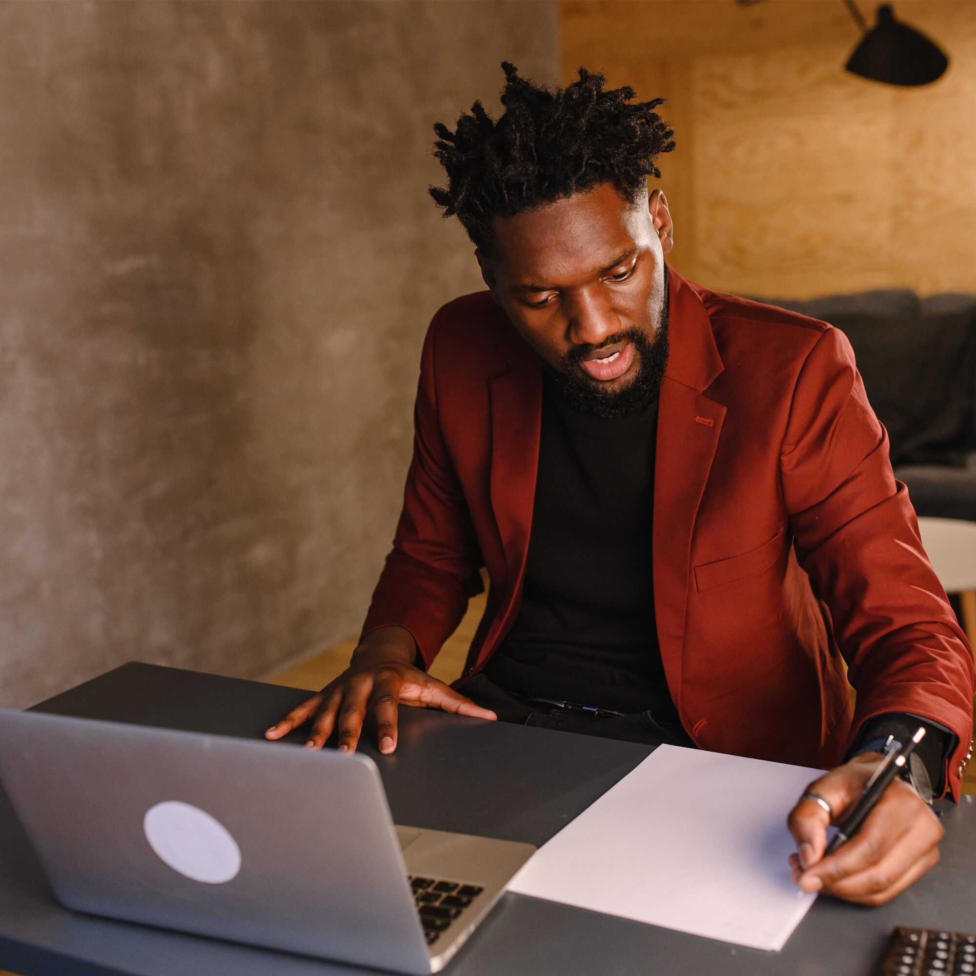 Male therapist in office writing notes while on computer